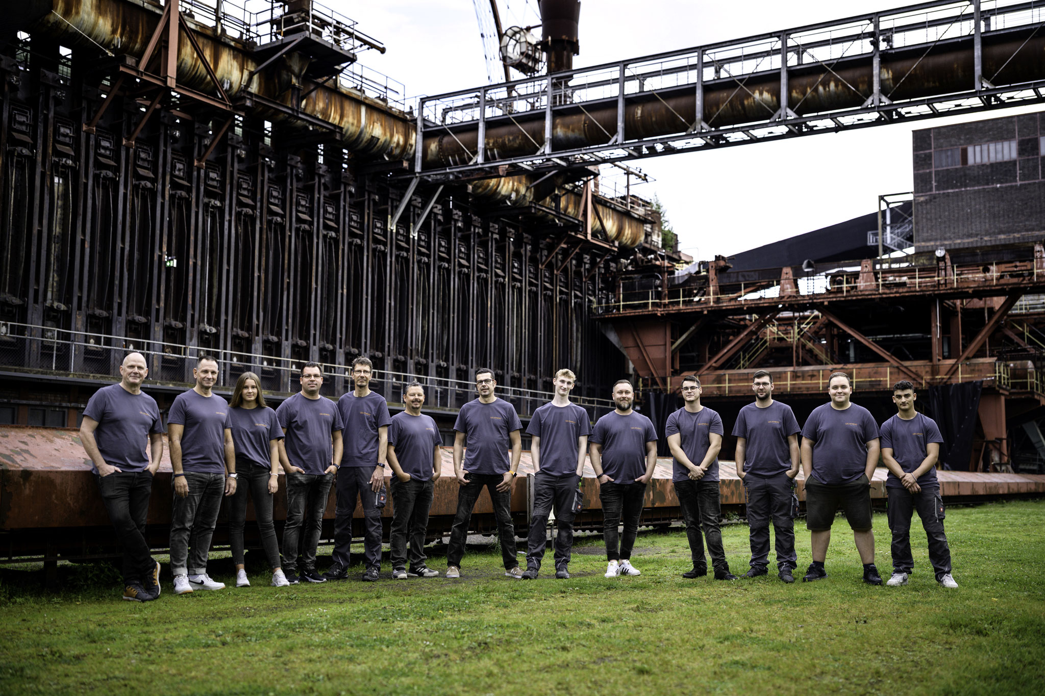 Zu sehen ist ein Gruppenfoto der Techniker von der Gelsenbad GmbH auf einem Rasen, direkt angrenzend zum Industriegebiet.
